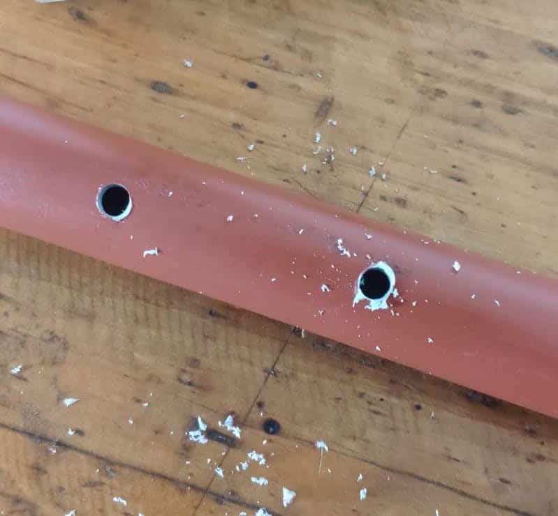 Antena FlowerPot VHF-UHF dañada con orificios en la base, en un entorno de taller.